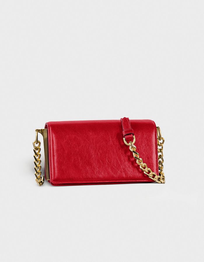 Red leather purse with gold chain strap on white background.